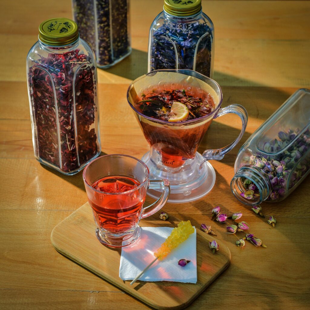 Herbal tea with lemon and honey, surrounded by glass jars filled with assorted dried flowers.